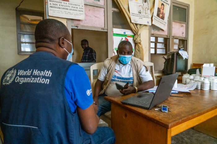 Dr. Mawanda (World Health Organization) and Chief Medical Officer, Dr. Goeth (right), discuss the enrollment of health workers into the mobile money program at the health zone office in Matadi, Democratic Republic of the Congo on June 4, 2021.